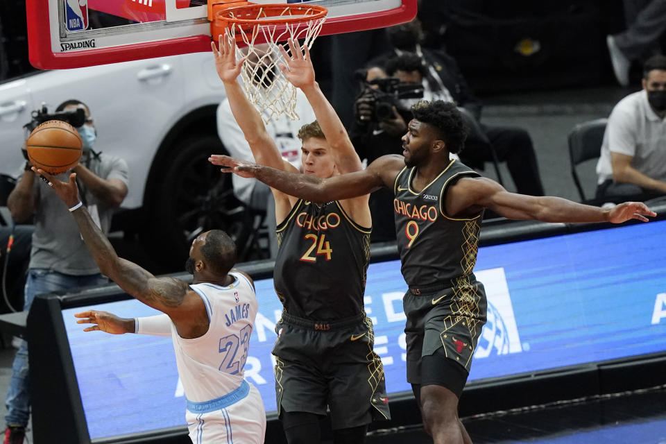 Los Angeles Lakers forward LeBron James, left, shoots against Chicago Bulls forward Lauri Markkanen, center, and forward Patrick Williams during the first half of an NBA basketball game in Chicago, Saturday, Jan. 23, 2021. (AP Photo/Nam Y. Huh)