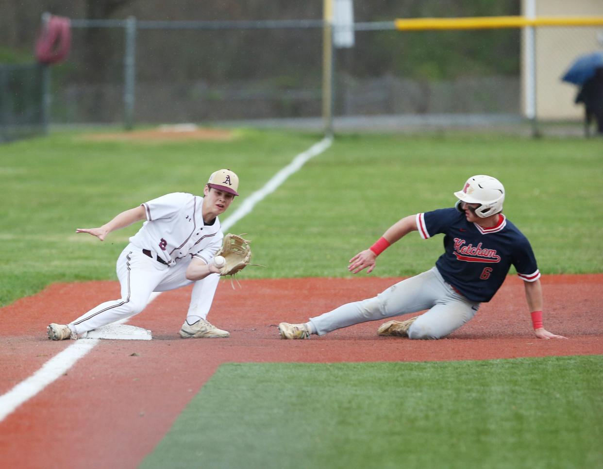 Roy C. Ketcham's Owen Paino slides into third base as Arlington's Christian Anderson covers the base during a game on April 17, 2024.