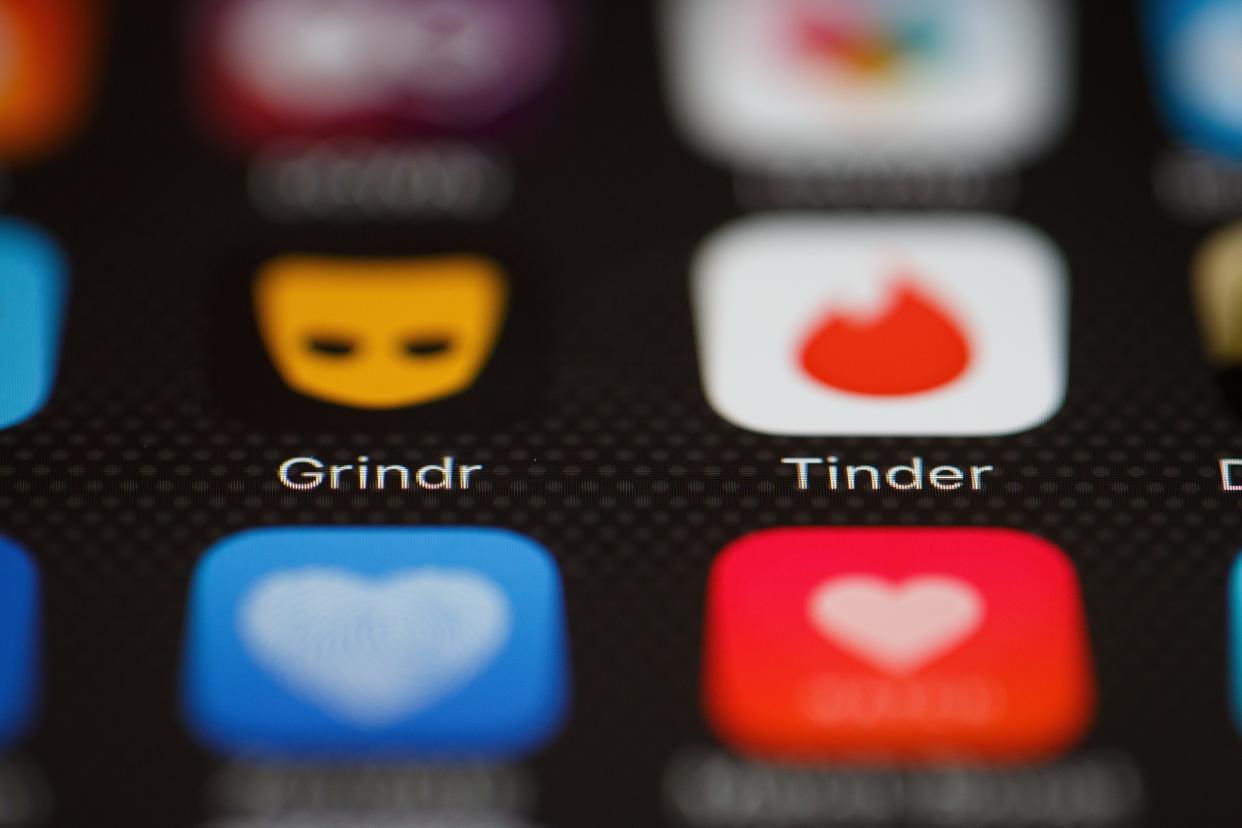 The Grindr and Tinder app logos are shown on a cellphone screen.