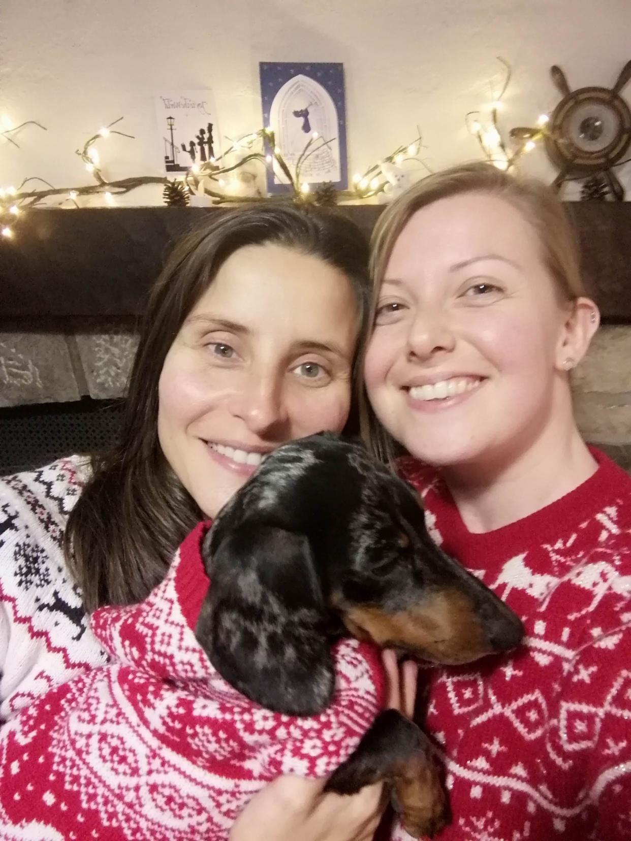 Anna (right), her wife (left), and their dog wearing Christmas sweaters