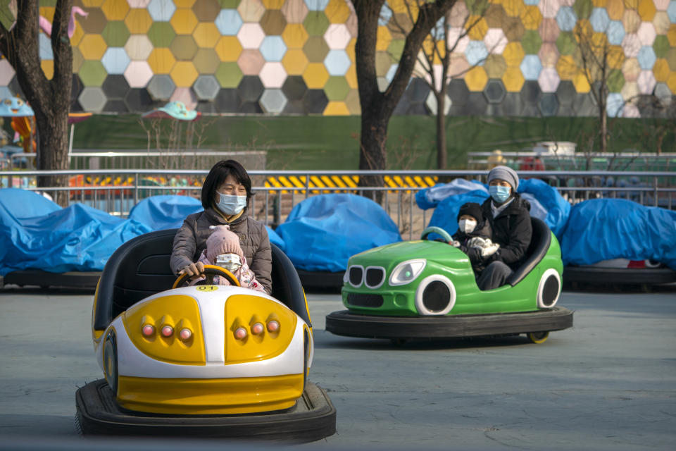 People wearing face masks to protect against the spread of the coronavirus ride on bumper cars at a public park in Beijing, Saturday, Jan. 2, 2021. Wary of another wave of infections, China is urging tens of millions of migrant workers to stay put during next month's Lunar New Year holiday, usually the world's largest annual human migration. (AP Photo/Mark Schiefelbein)