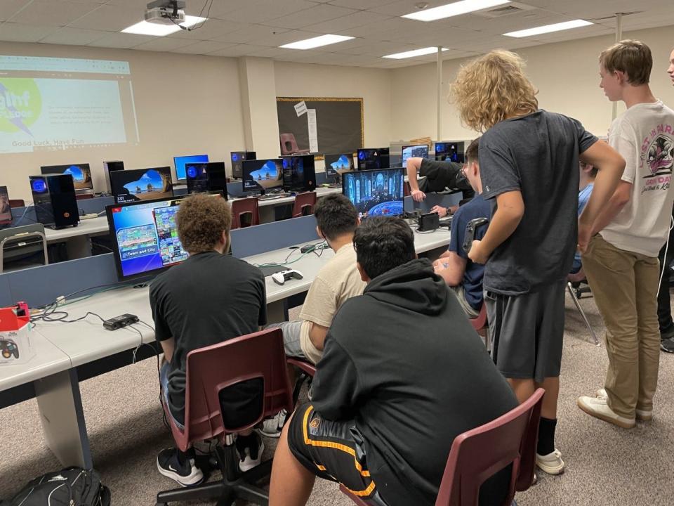 Gilbert High School esports members huddled around a computer, watching a match.