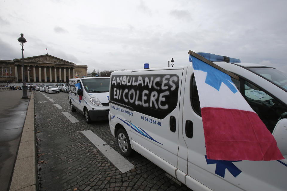 Ambulance workers block the bridge leading the National Assembly, background, Monday, Dec. 3, 2018 in Paris. Ambulance workers took to the streets and gathered close to the National Assembly in downtown Paris to complain about changes to working conditions as French Prime Minister Edouard Philippe is holding crisis talks with representatives of major political parties in the wake of violent anti-government protests that have rocked Paris. On ambulance reads: Angry ambulance workers. (AP Photo/Michel Euler)