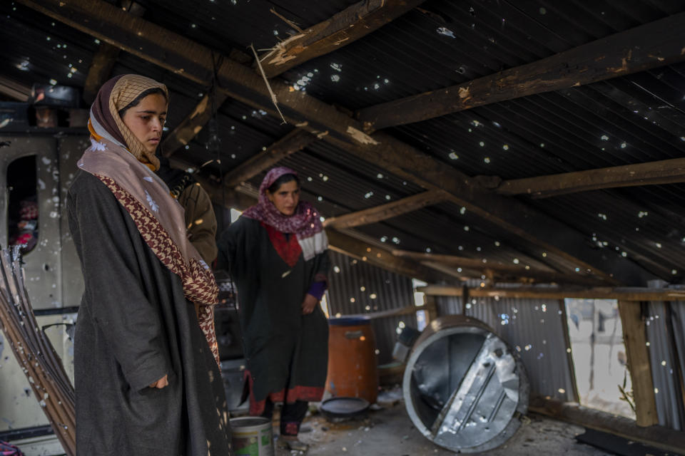 Kashmiri women stand under the bullet ridden tin roof of a damaged residential house where suspected rebels had taken refuge, after a gunfight in Kulgam south of Srinagar, Indian controlled Kashmir, Friday, Nov. 17, 2023. Police in Indian-controlled Kashmir said government forces killed five suspected militants in a gunbattle on Thursday. (AP Photo/Dar Yasin)