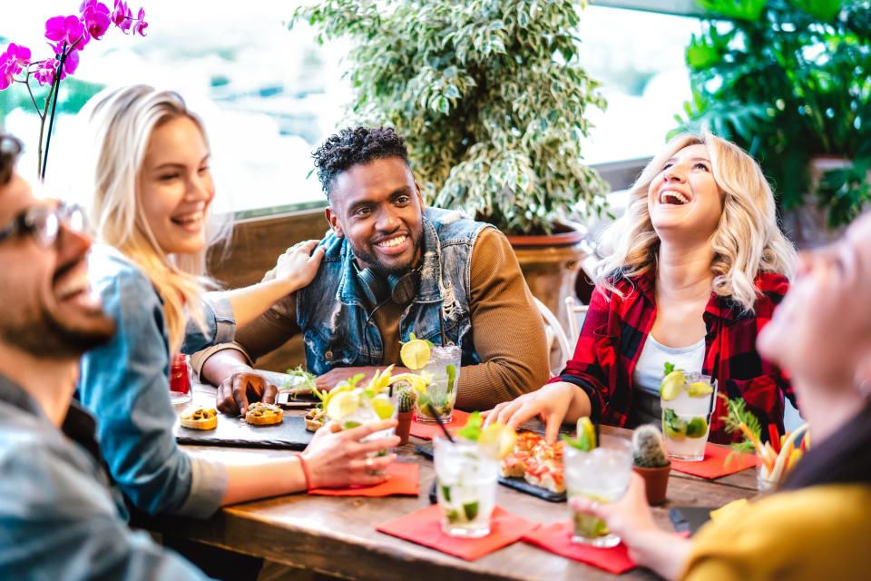 Young people sat together in a restaurant with food and drinks