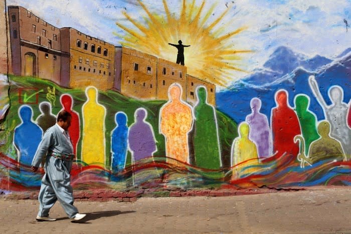 An Iraqi Kurdish man walks past a mural in the square in the citadel in Arbil, the capital of the autonomous Kurdish region of northern Iraq (Safin Hamed / Getty)