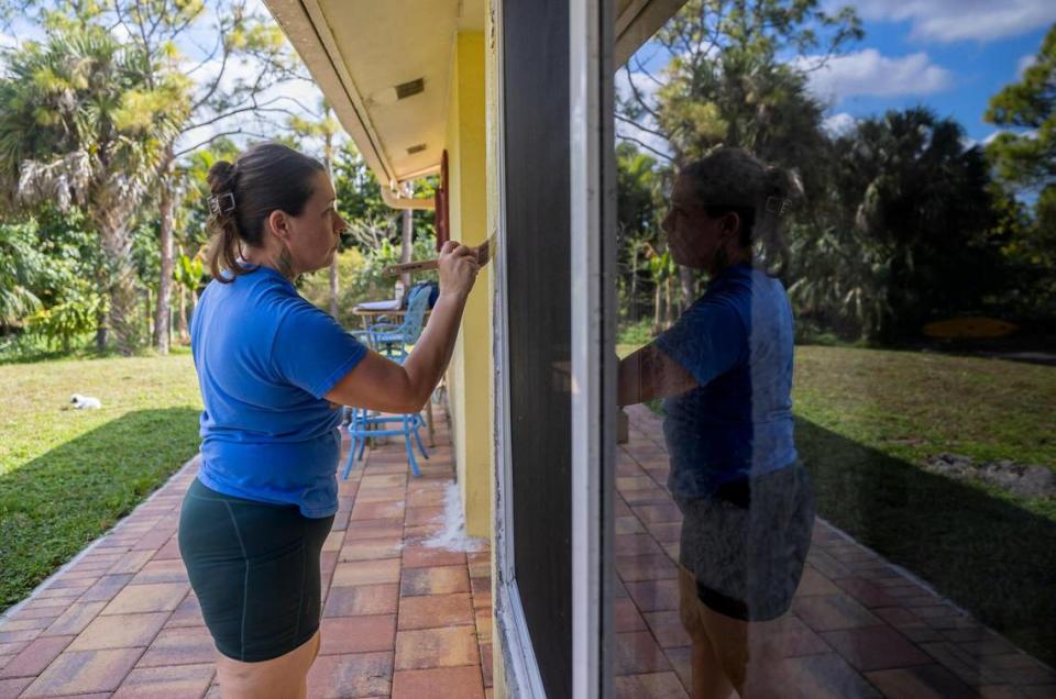 Kelly Coulter, de 44 años, pintando la moldura de sus ventanas de impacto recién instaladas el miércoles 31 de enero de 2023, en West Palm Beach, la Florida. Coulter y su esposo, Ray, usaron la financiación Ygrene para financiar un nuevo techo y ventanas de impacto antes de que Ygrene retirara la financiación para todos en la Florida.