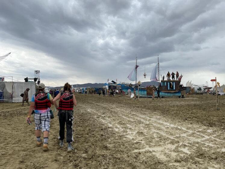 TOPSHOT - Attendees walk through a muddy desert plain on September 2, 2023, after heavy rains turned the annual Burning Man festival site in Nevada's Black Rock desert into a mud pit. Tens of thousands of drenched festivalgoers were stranded on September 3, 2023, in deep, sticky mud in the Nevada desert after torrential rain turned the annual Burning Man gathering into a quagmire. All events at the counterculture festival, which drew some 70,000 people, were canceled after rain tore down structures for dance parties, art installations and other eclectic entertainment. (Photo by Julie JAMMOT / AFP) (Photo by JULIE JAMMOT/AFP via Getty Images)