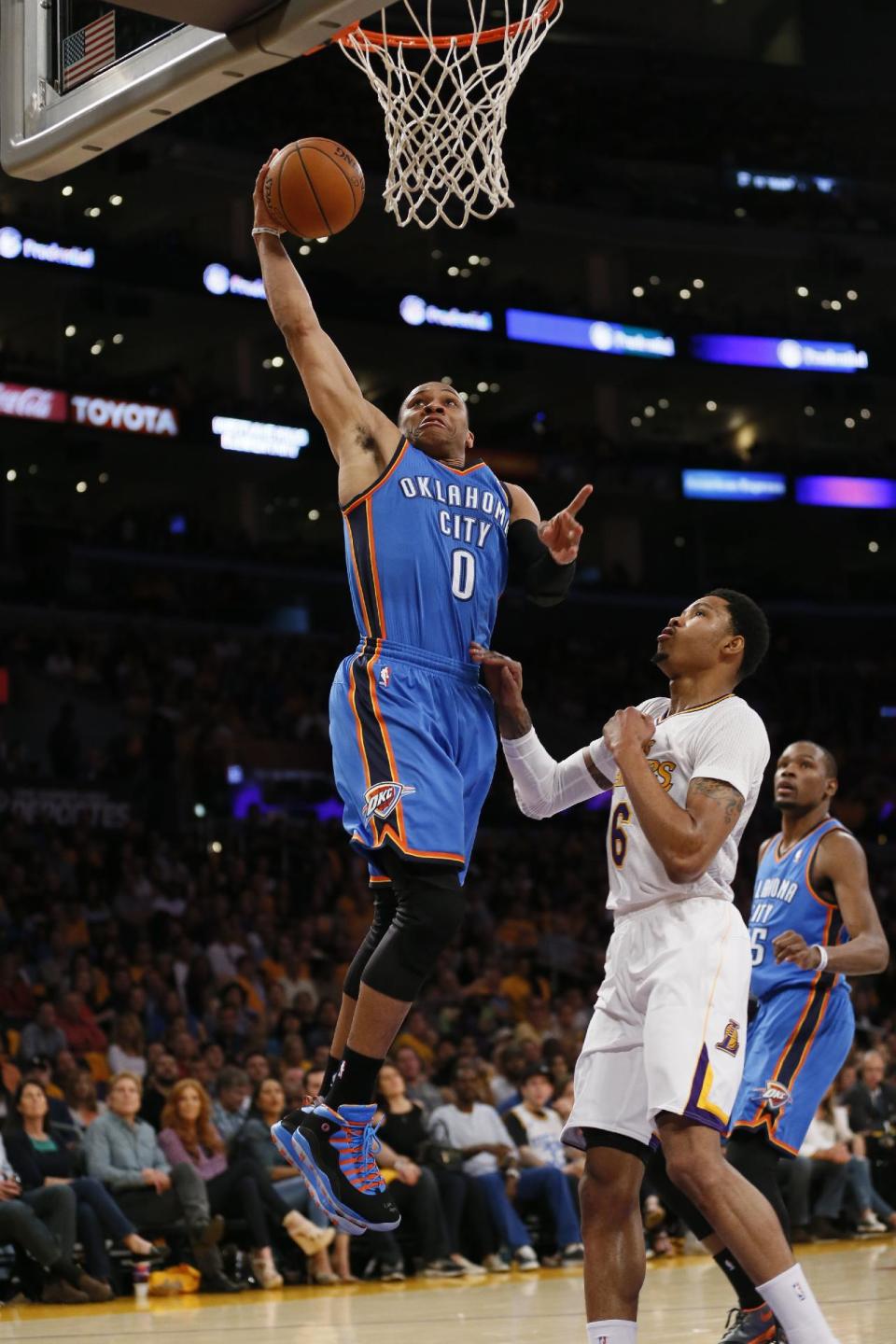 Oklahoma City Thunder point guard Russell Westbrook, left, goes to the hoop over Los Angeles Lakers shooting guard Kent Bazemore during the first half of an NBA basketball game in Los Angeles, Sunday, March 9, 2014. (AP Photo/Danny Moloshok)
