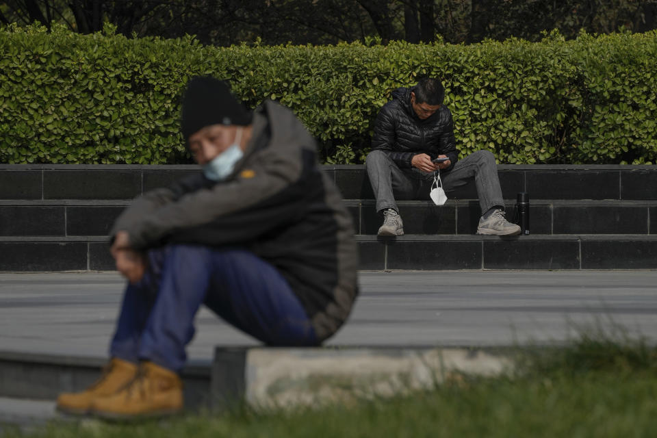 People with their face masks take a rest outside an office building during a lunch break hour in Beijing, Wednesday, Nov. 2, 2022. (AP Photo/Andy Wong)