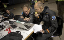 Solar Impulse pilots Bertrand Piccard, right, and Andre Borschberg, center, check the weather conditions before taking off at Barajas airport in Madrid, Spain, Tuesday, June 5, 2012. The experimental solar-powered airplane arrived in Madrid on May 25, 2012 from Payerne, Switzerland, and now goes on to Rabat, Morocco on its first transcontinental trip. The mission is described as the final dress rehearsal for a round-the-world flight with a new and improved aircraft in 2014. (AP Photo/Alberto Di Lolli)