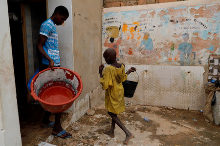 Moussa, a Koran student, called a talibe, from Futa, carries a bucket of water to take a shower at Maison de la Gare, an organisation that helps talibe street children reintegrate into society, in Saint-Louis, Senegal, February 7, 2019. REUTERS/Zohra Bensemra