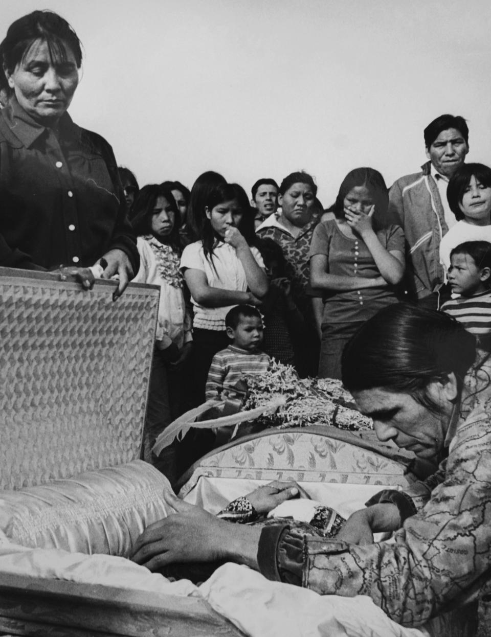 FILE - American Indian Movement leader Dennis Banks leans into the casket of an AIM member killed by U.S. marshals in Wounded Knee, S.D., in February 1973. (AP Photo/Jim Mone, File)