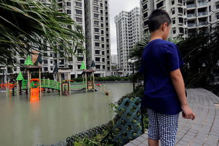 A child stands next to a flooded playground after Typhoon Hato hits Hong Kong, China August 23, 2017. REUTERS/Tyrone Siu