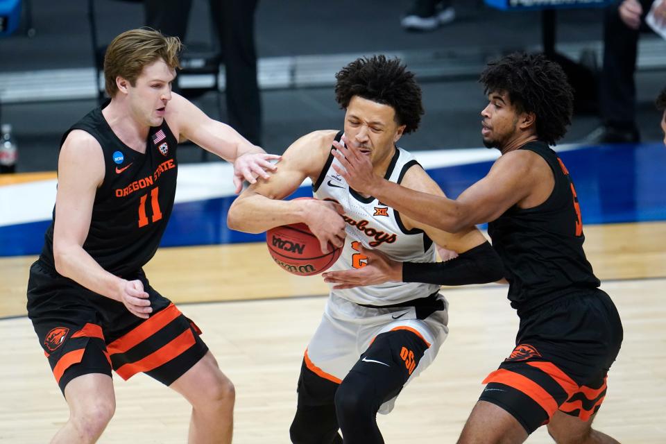 Oklahoma State guard Cade Cunningham (2) drives between Oregon State guard Zach Reichle (11) and Ethan Thompson (5) during the first half Sunday at Hinkle Fieldhouse in Indianapolis.