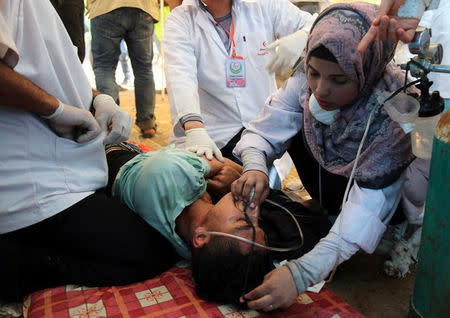 Shorouq Abu Musameh, who volunteers with other paramedics, tends to a Palestinian who inhaled tear gas fired by Israeli troops during a protest where Palestinians demand the right to return to their homeland, at the Israel-Gaza border, in the southern Gaza Strip April 13, 2018. REUTERS/Samar Abo Elouf