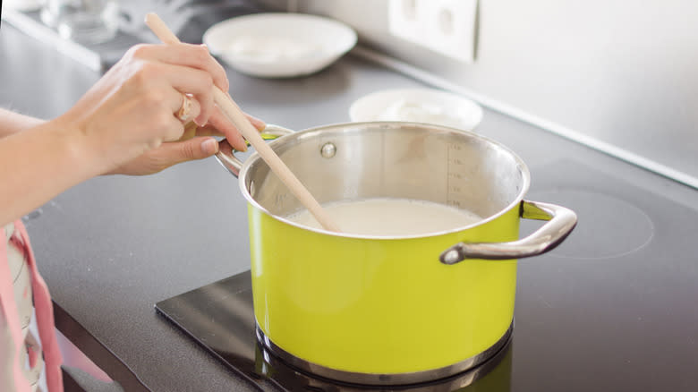 person stirring stovetop bechamel sauce