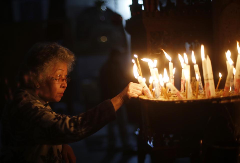 A woman holds a burning candle during a visit to the Church of Nativity in Bethlehem on Christmas day