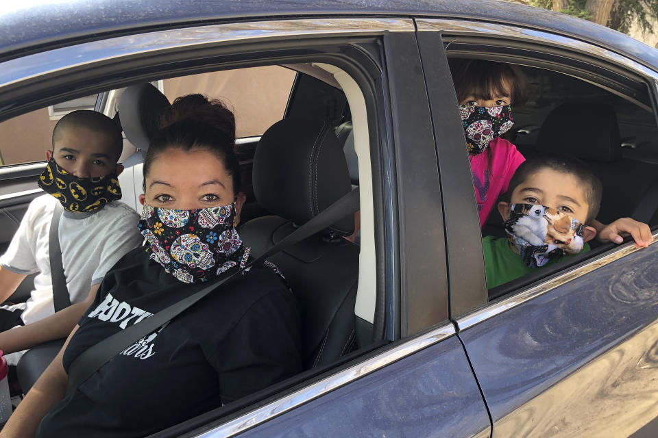 Ashley Pyne, foreground left, brings her three children to drive-through coronavirus testing at the Native American community of Picuris Pueblo, N.M., Thursday, April 23, 2020. Small Native American pueblo tribes across New Mexico are embracing extraordinary social distancing measures that include guarded roadblocks and universal testing for the coronavirus in efforts to insulate themselves from a contagion with frightening echoes of the past. (AP Photo/Morgan Lee)