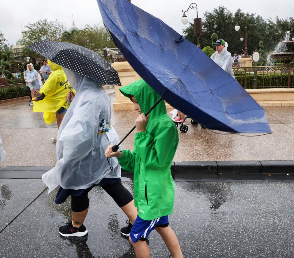 Winds blow an umbrella inside-out as guests leave the Magic Kingdom at Walt Disney World in Lake Buena Vista, Fla., Wednesday, Nov. 9, 2022, as conditions deteriorate with the approach of Hurricane Nicole.