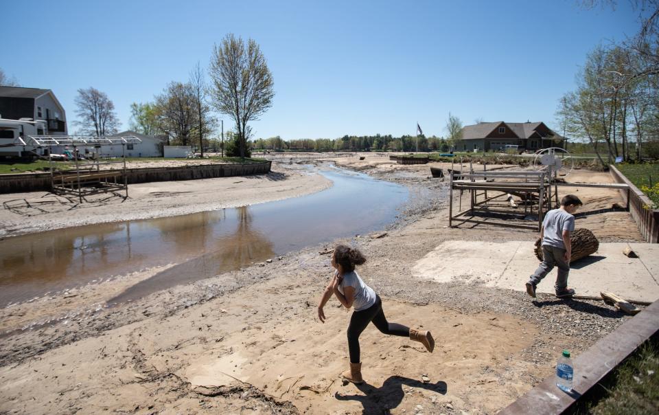 Hailey Holsinger of Bay City and her brother Gabe throw rocks into the little water remaining behind their family's home along Wixom Lake in Beaverton on May 21 after the Edenville Dam broke.