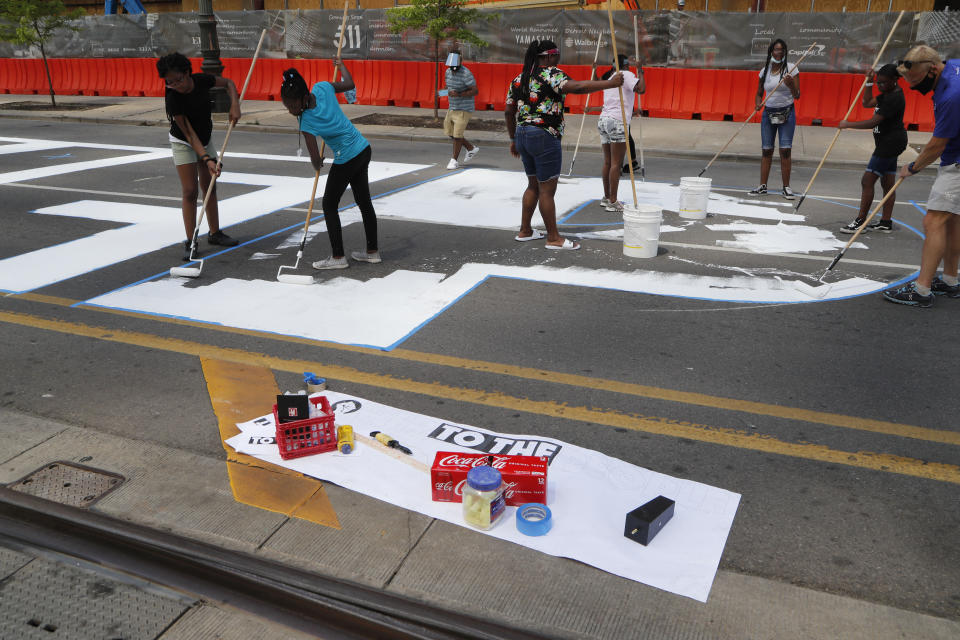 In this Wednesday, June 17, 2020, photo, Detroit public schools students and youths with Detroit Heals Detroit, a social justice organization that helps Detroit youths who have suffered trauma, paint a mural on Woodward Ave in Detroit. The mural, funded by the Knight Foundation and Bedrock, will spell out "Power to the People". (AP Photo/Carlos Osorio)