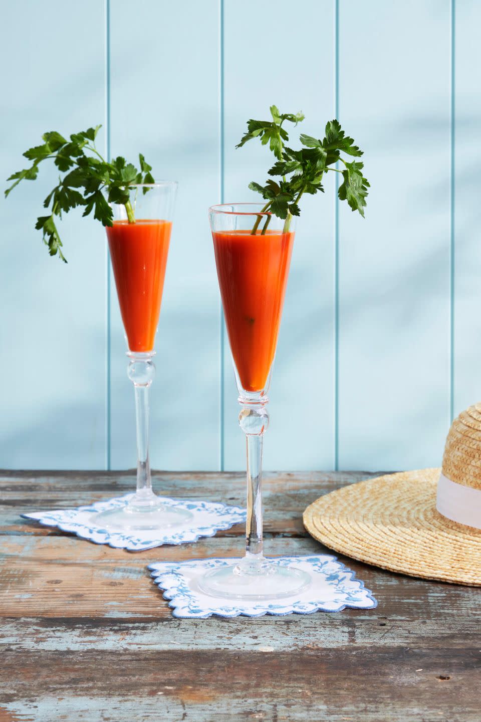 a tall champagne glass filled with carrot juice and topped with a sprig of parsley to look like carrot greens