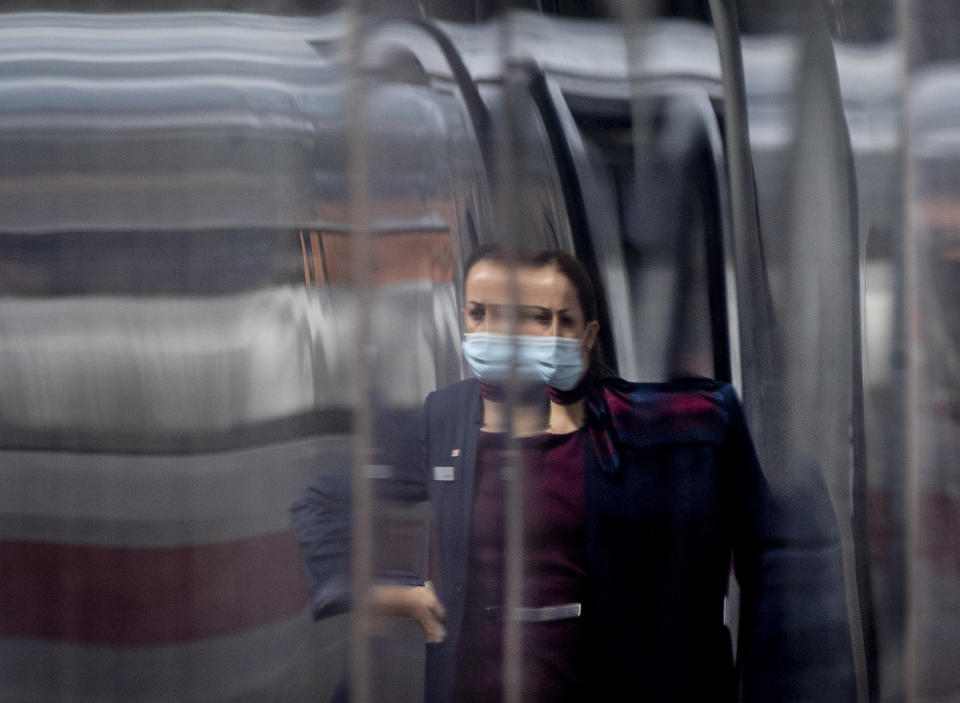 A conductor is reflected in a parked ICE train in the main train station in Frankfurt, Germany, Thursday, Aug. 27, 2020. An announcement of German Chancellor Angela Merkel about the further strategy to avoid the outspread of the Coronavirus is expected later today. (AP Photo/Michael Probst)