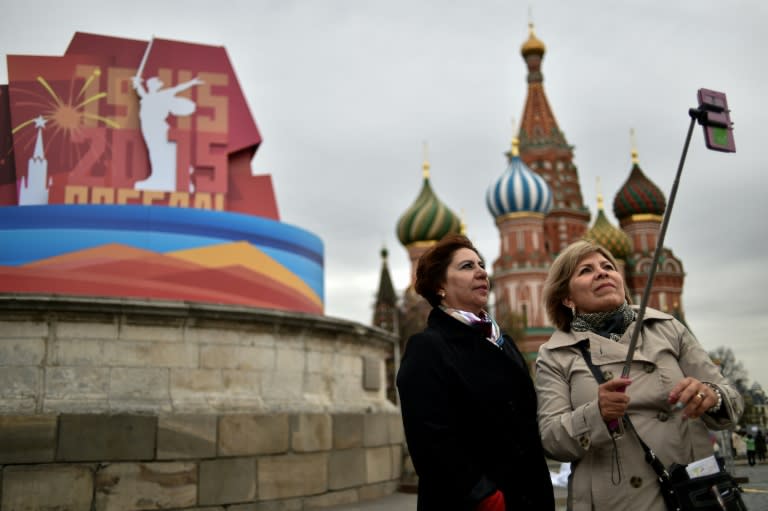 Women pose for a selfie in front of the historical Place of Execution decorated with a banner for the upcoming Victory Day celebrations on the Red Square in central Moscow, on April 30, 2015