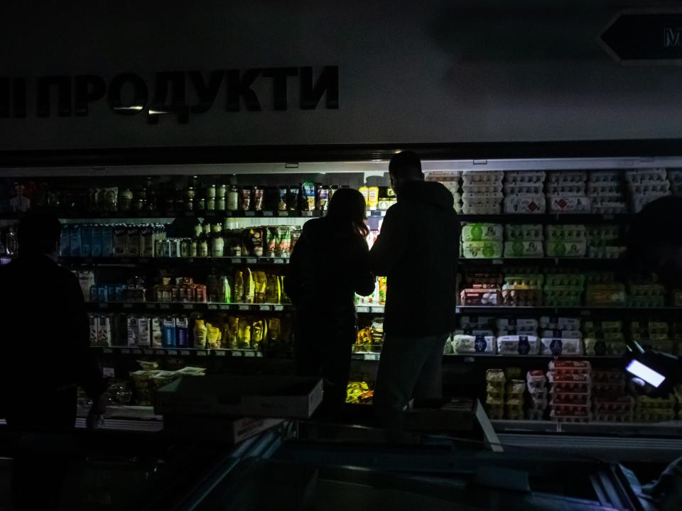 Two people are illuminated by a light in grocery store aisle.