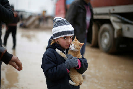 Malac, a 7-year-old, holds her cat as she walks back with her family to their home from Khazer camp, Iraq. REUTERS/Muhammad Hamed