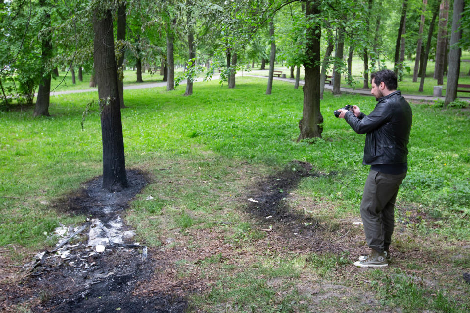 A man takes photos of fragments of Russian missiles that fell on a grassy area of the zoo in Kyiv.