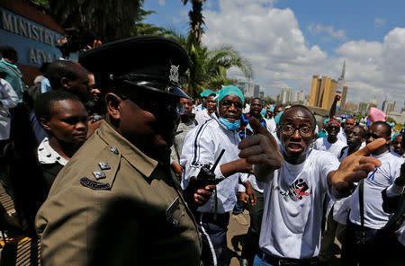 Kenyan doctors speak to a policeman attempting to disperse them during a strike to demand fulfilment of a 2013 agreement between their union and the government that would raise their pay and improve working conditions outside Ministry of Health headquarters in Nairobi, Kenya December 5, 2016. REUTERS/Thomas Mukoya