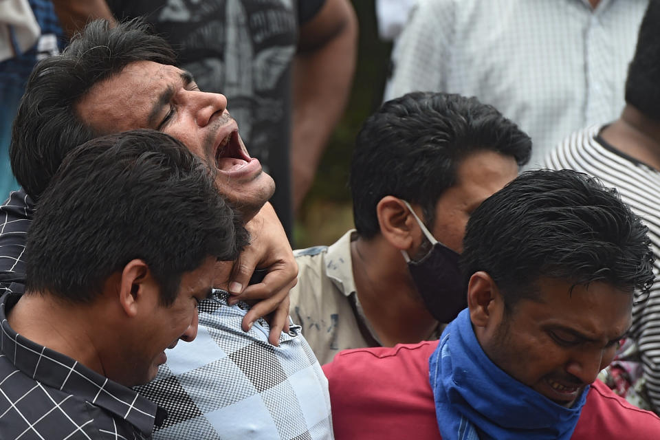 Relatives mourn the death of a victim who died after a five-storey apartment building collapsed in Mahad. (Photo by PUNIT PARANJPE/AFP via Getty Images)