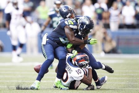 Sep 21, 2014; Seattle, WA, USA; Seattle Seahawks strong safety Kam Chancellor (31) and defensive back Marcus Burley (28) break up a pass intended for Denver Broncos wide receiver Emmanuel Sanders (10) during the fourth quarter at CenturyLink Field. Joe Nicholson-USA TODAY Sports - RTR475R6