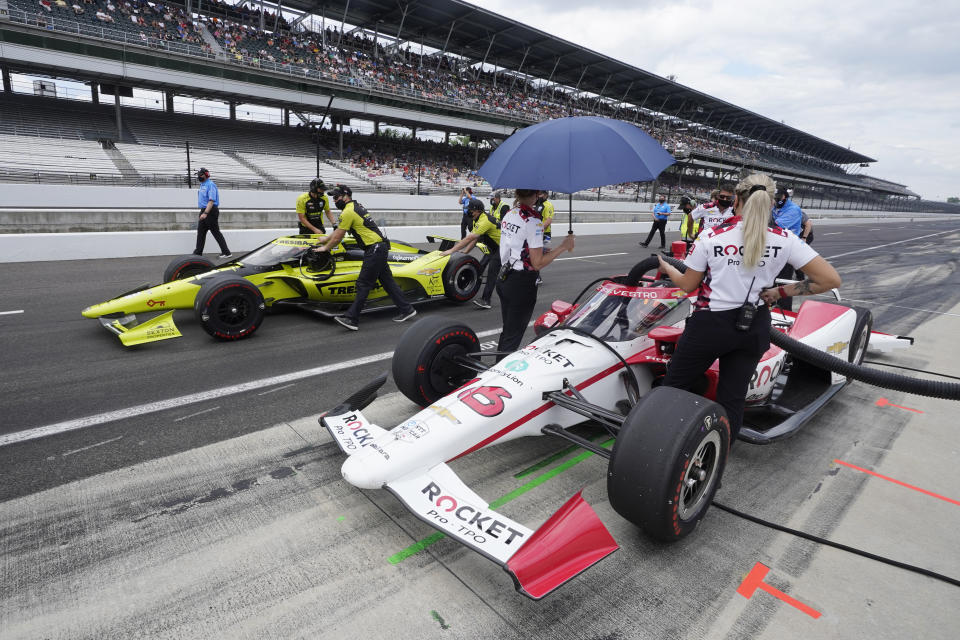 Simona De Silvestro, foreground, of Switzerland, sits in her car as the crew of Charlie Kimball pushes his car to the qualification line during qualifications for the Indianapolis 500 auto race at Indianapolis Motor Speedway, Sunday, May 23, 2021, in Indianapolis. (AP Photo/Darron Cummings)