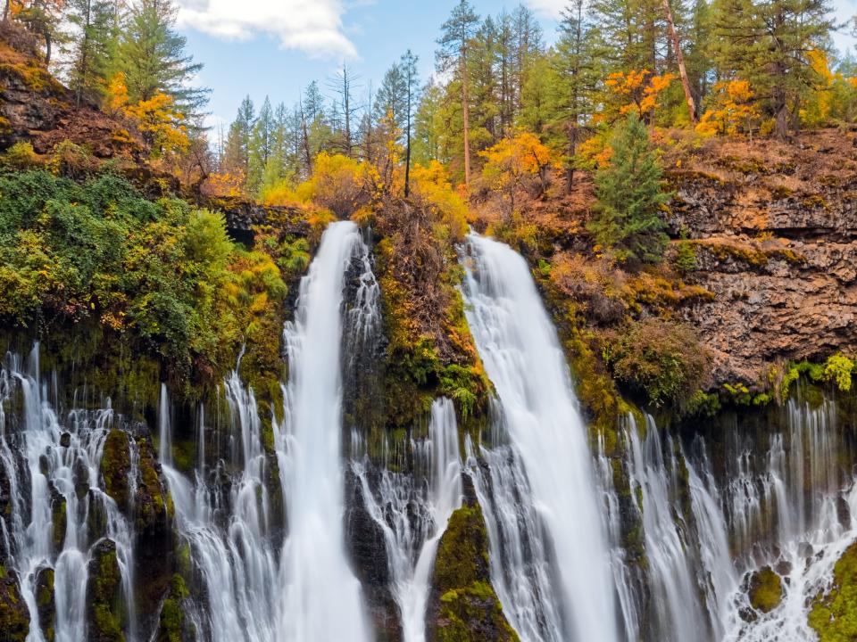 Waterfall in autumn with green and yellow trees at the top at McArthur-Burney Falls Memorial State Park, in Shasta County, Northern California