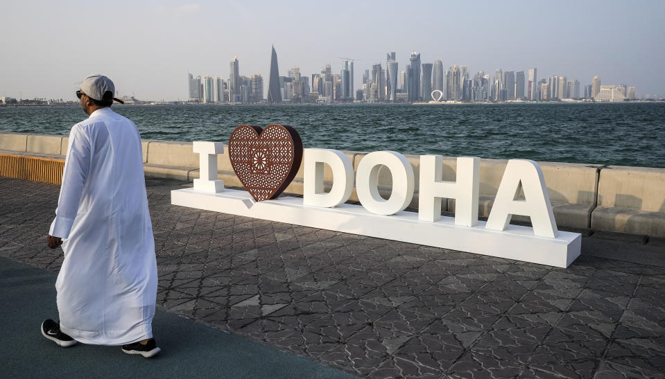 A man walks at the Doha Corniche in front of the skyline on the day before the start of the Soccer World Cup in Doha, Qatar, Saturday, Nov. 19, 2022. (AP Photo/Martin Meissner)