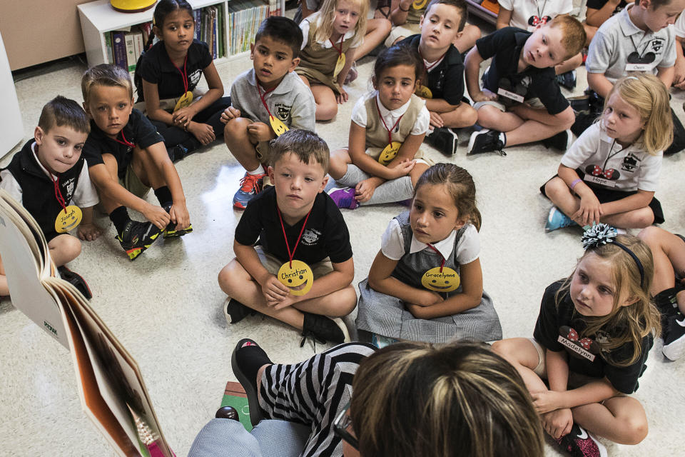 FILE — In this Aug. 22, 2018, file photo, students from two kindergarten classes at the Lewiston elementary campus of Saint Dominic Academy, listen to a teacher read a book, in Lewiston, Maine. School districts across the United States are hiring additional teachers in anticipation of what will be one of the largest kindergarten classes ever as enrollment rebounds following the pandemic. (Russ Dillingham/Sun Journal via AP, File)