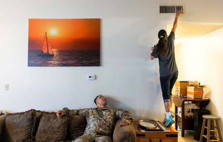 FILE PHOTO: Leanne Bell, 39, checks the air quality of a vent as her husband, Spc. Tevin Mosley, 26, looks on while waiting for a maintenance crew to arrive at the army base housing allocated to the family in Fort Hood, Texas, U.S on May 16, 2019. The family says they began suffering breathing issues, depression, and rashes they attribute to a mold infestation and were forced to vacate the home in March after it was put under quarantine while repairs were made. Despite the repairs, mold can visibly be seen on surfaces throughout the home. REUTERS/Amanda Voisard