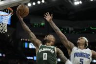 Damian Lillard de los Bucks de Milwaukee lanza el balón superando a Paolo Banchero del Magic de Orlando en el encuentro de la NBA del miércoles 10 de abril del 2024. (AP Foto/Morry Gash)