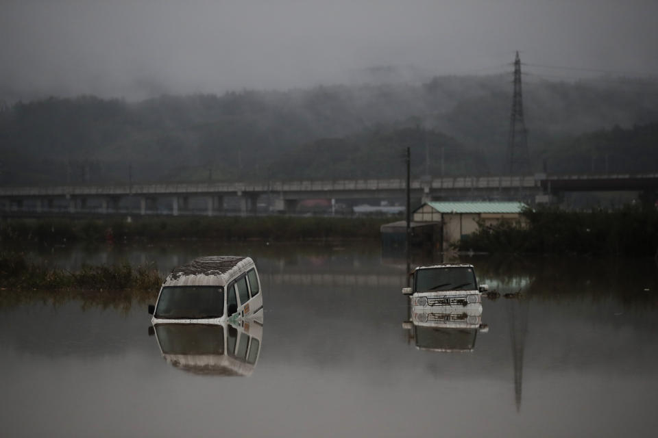 Two vehicles are submerged in floodwaters Monday, Oct. 14, 2019, in Hoyasu, Japan. Rescue crews in Japan dug through mudslides and searched near swollen rivers Monday as they looked for those missing from a typhoon that left as many as 36 dead and caused serious damage in central and northern Japan. (AP Photo/Jae C. Hong)