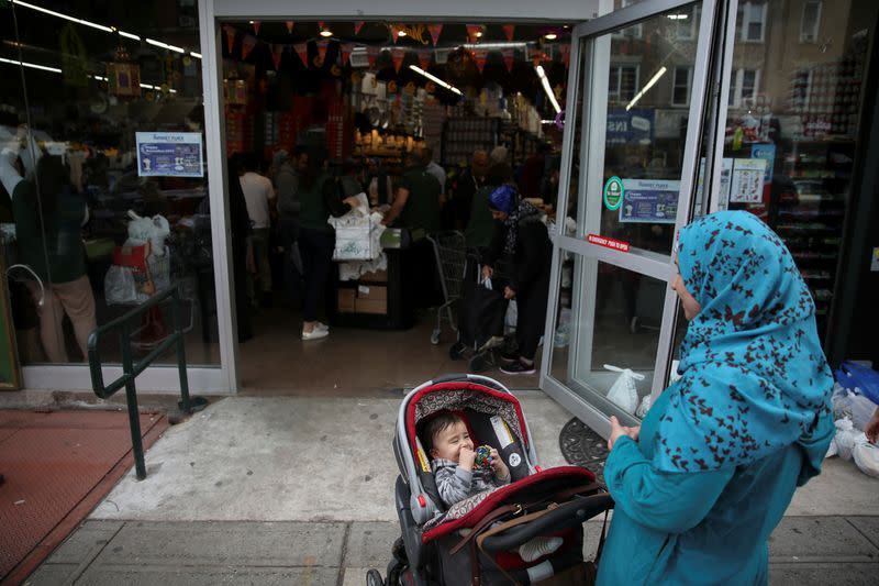 A Muslim American woman wearing hijab awaits outside the Balady halal supermarket with a child ahead of the first day of Ramadan in Brooklyn, New York