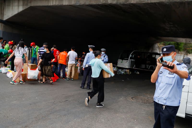 People deliver food near a residential compound that is under lockdown in the Fengtai district, in Beijing