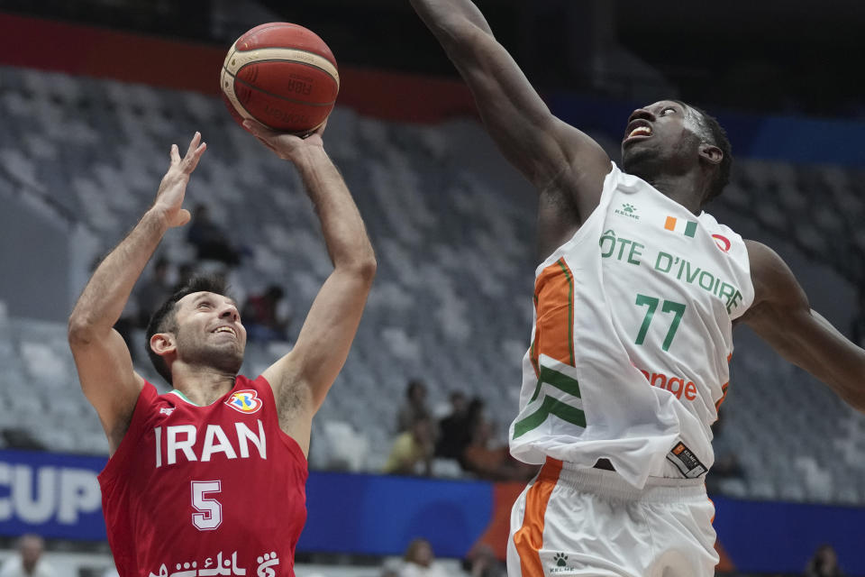 Iran guard Sajjad Mashayekhi (5) drives past Cote D'Ivoire forward Jean Philippe Dally (77) during the Basketball World Cup group G match between Cote d'Ivoire and Iran at the Indonesia Arena stadium in Jakarta, Indonesia, Monday, Aug. 28, 2023. (AP Photo/Tatan Syuflana)