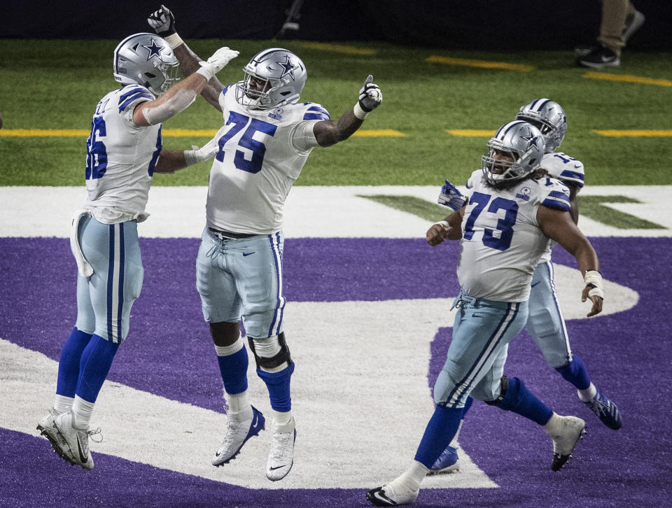 Dallas Cowboys offensive tackle Cameron Erving (75) celebrates tight end Dalton Schultz's (86) winning touchdown catch in the fourth quarter of an NFL football game against the Minnesota Vikings in Minneapolis, Sunday, Nov. 22, 2020. (Jerry Holt/Star Tribune via AP)