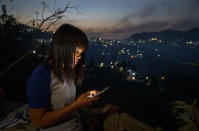 A police officer who fled Myanmar following a military coup looks at her phone at an undisclosed location bordering Myanmar, in the northeastern Indian state of Mizoram, Thursday, March 18, 2021. Villagers in Mizoram have given shelter to 34 Myanmar police personnel and 1 fire fighter, who crossed over to the state over the last two weeks. Those who escaped spend their time watching local television and doing daily chores. Some of them have carried mobile phones and are trying to connect to families they were forced to leave behind. At night, all of them go to sleep on mattresses laid on the floor of a single room. (AP Photo/Anupam Nath)