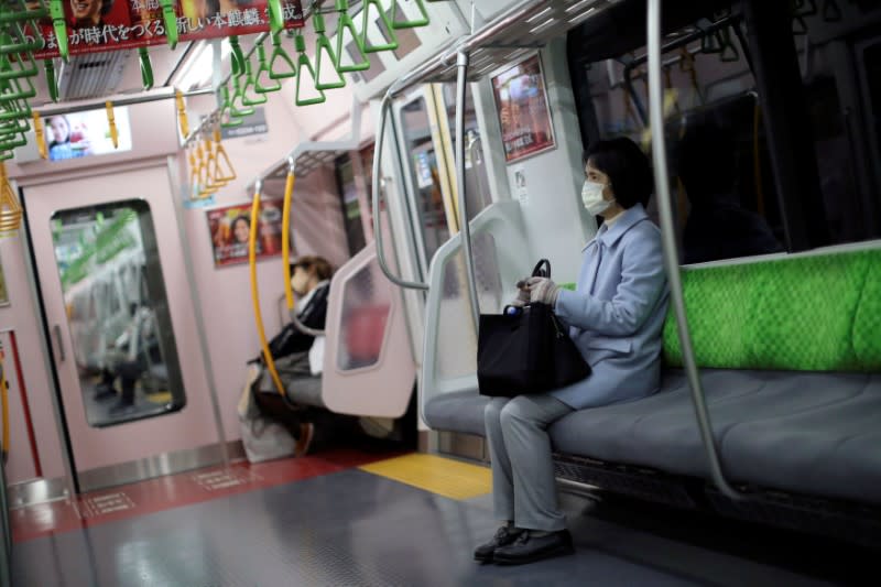 FILE PHOTO: A woman, wearing a protective mask following an outbreak of the coronavirus disease (COVID-19), sits in a subway train in Tokyo