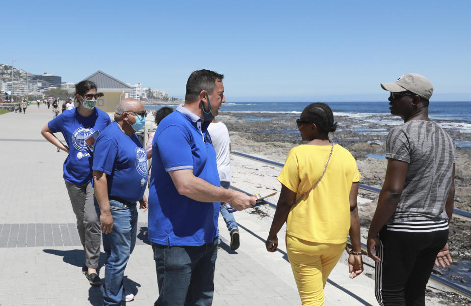 John Steenhuisen, leader of South Africa's largest opposition party, the Democratic Alliance, center, speaks to passers by in Sea Point in Cape Town, South Africa, Saturday Oct. 30, 2021. As South Africa heads to crucial local elections, the country has been hit by a series of crippling power blackouts that many critics say highlight poor governance. (AP Photo/Nardus Engelbrecht)