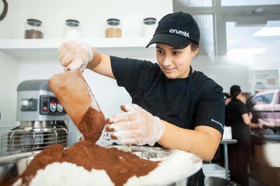 Crumbl Cookies baker Zoe, 18, of Merced, measures ingredients for Molten Lava cookie dough, at Crumbl Cookies, located at 3630 G Street, Suite E, in the new Yosemite Crossing shopping center in Merced, Calif., on Wednesday, June 7, 2023. The location’s grand opening is scheduled for June 9.